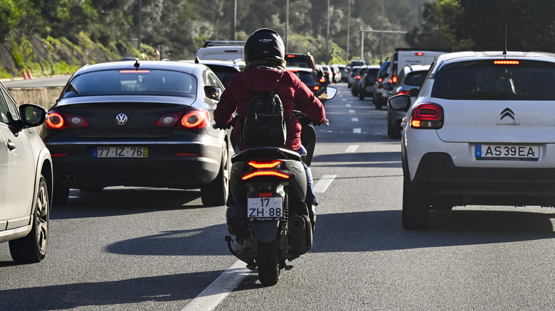 A motorcycle rider on a packed highway.