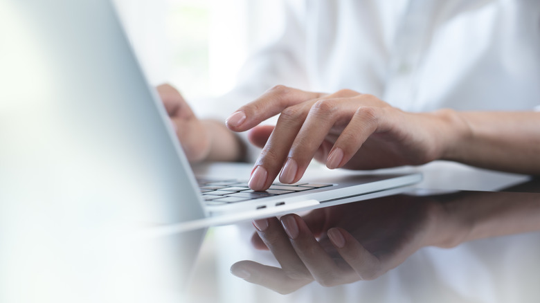 Close up of hands typing on a laptop keyboard