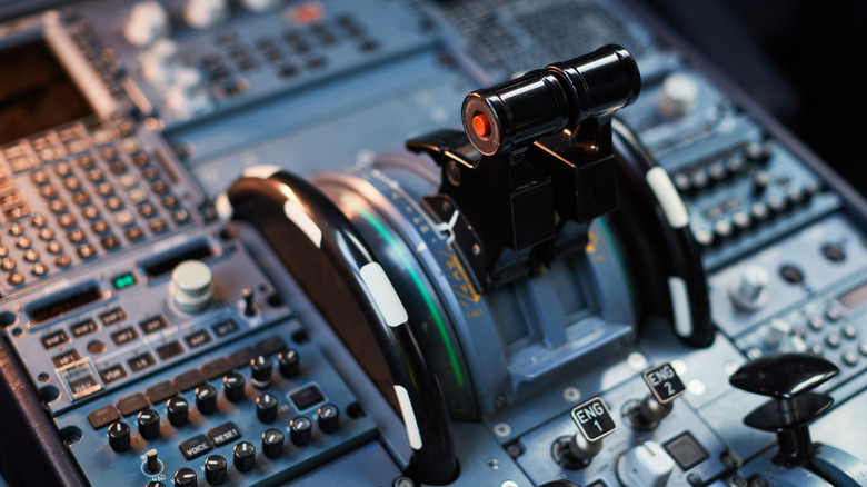 Levers and buttons on an aircraft's cockpit control panel.