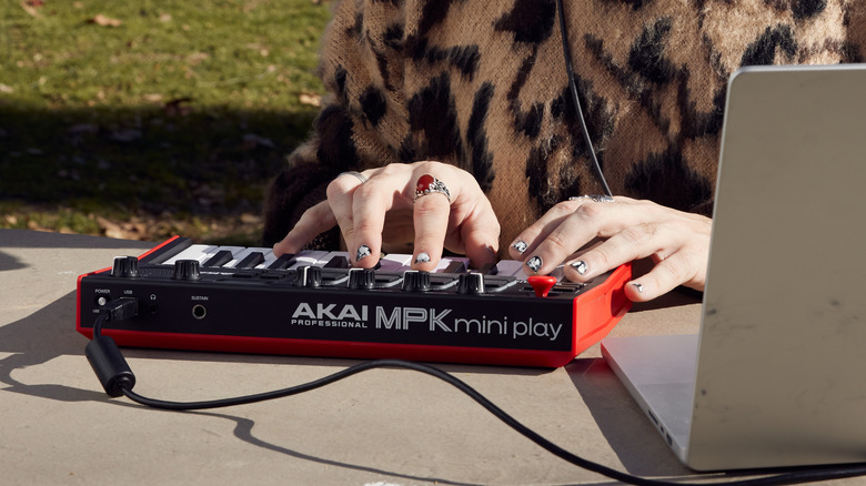 Musician using Akai Mini Play MK3 MIDI keyboad with laptop