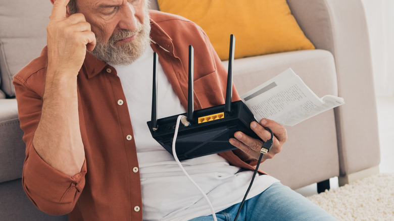 Man trying to fix Wi-Fi router on living room floor