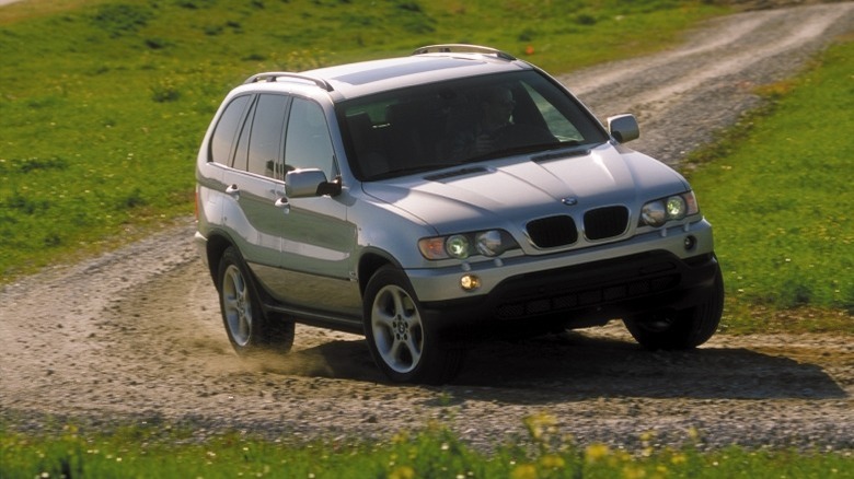 A silver X5 skidding round a bend on a dirt road