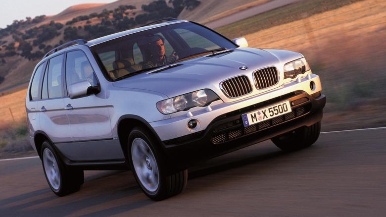 a silver X5 in blurred motion on a rural road