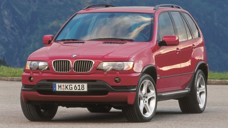 A red BMW x 5 parked in a car park with mountains in the background