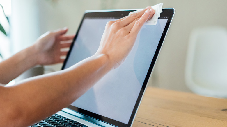 person wiping laptop screen