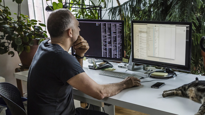 man working on two computer monitors