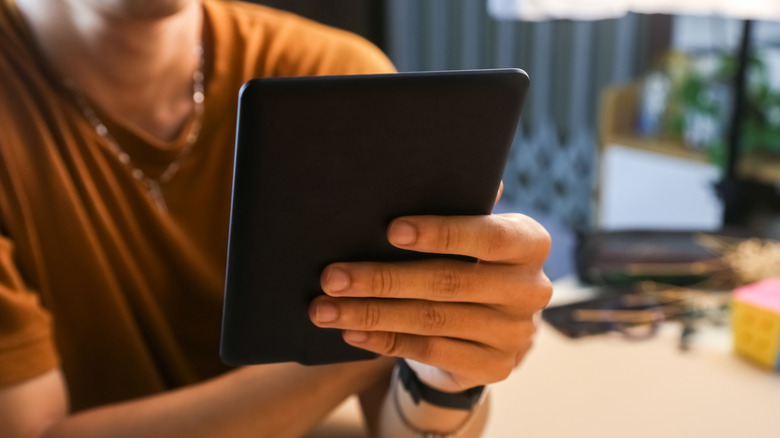 A faceless person is holding an e-reader