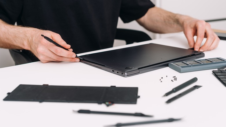 man repairing laptop under warranty