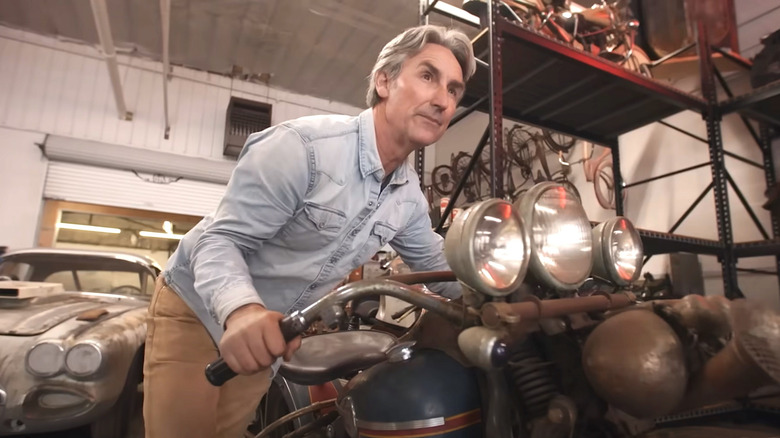 Mike Wolfe pushing one of his rare motorcycles around his storage facility.