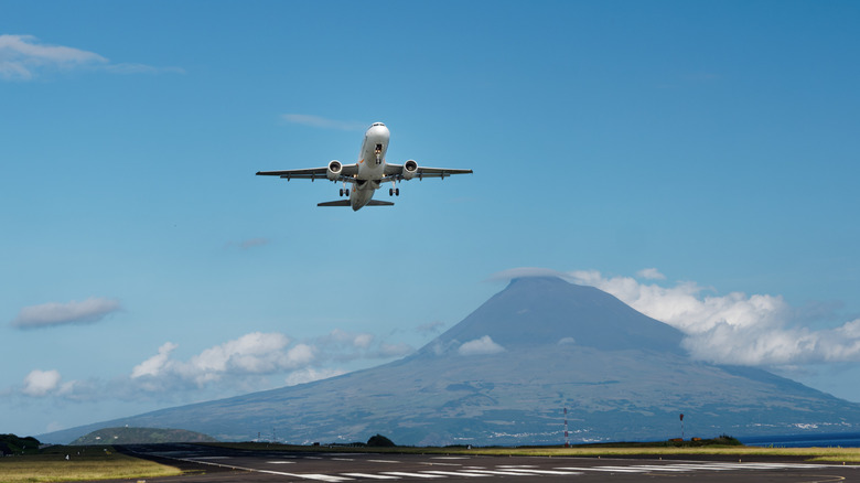 A plane taking off with a volcanic mountain in the background