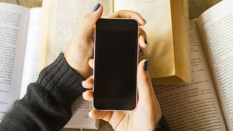 hand holding phone over books