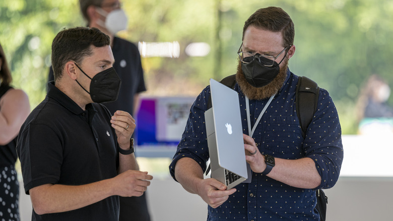 Two people examining MacBook