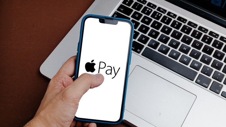 Person holding iPhone with Apple Pay logo on the screen