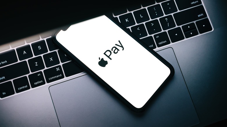 Apple Pay logo on an iPhone placed on a MacBook.