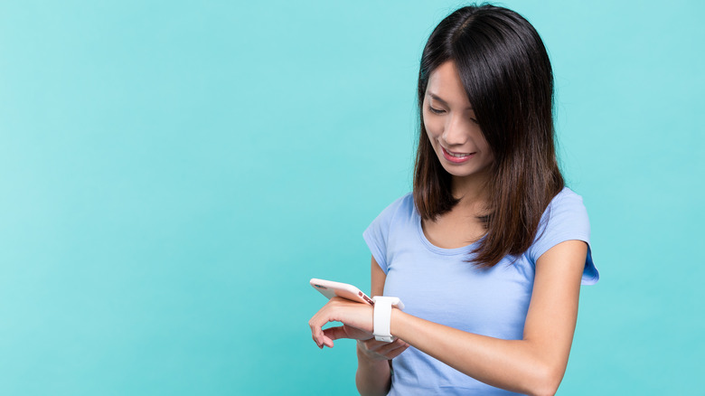 Person holding phone near smartwatch