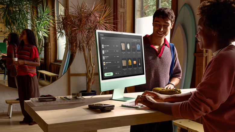 A person using the 24-inch iMac with M4 processor while another person looks at it