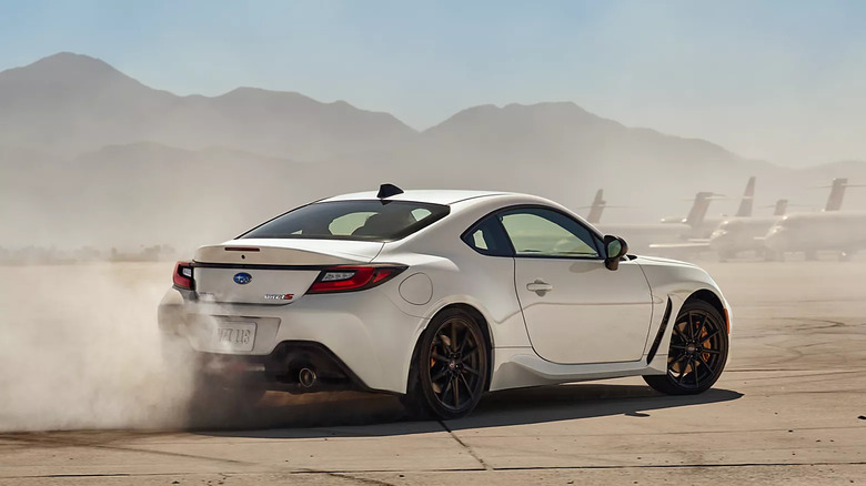 White 2025 Subaru BRZ tS drifting on a paved surface with mountains and airplanes in the background