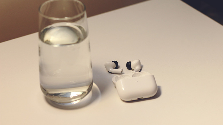 AirPods next to a glass of water