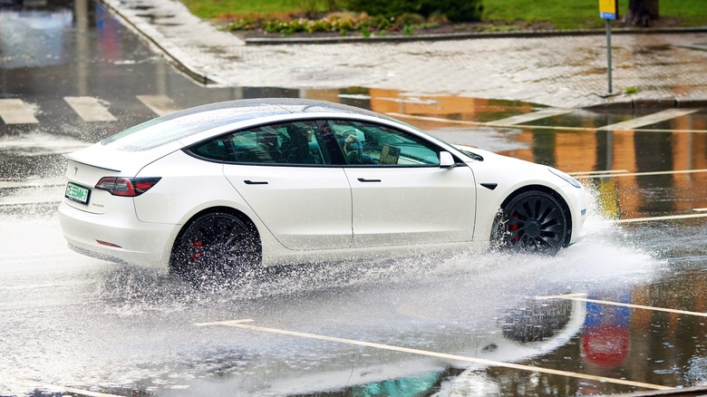 White Tesla driving in large puddle