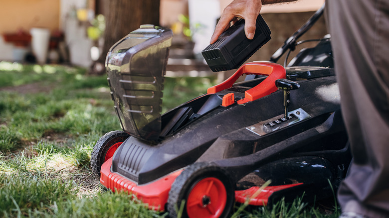 person replacing battery electric mower