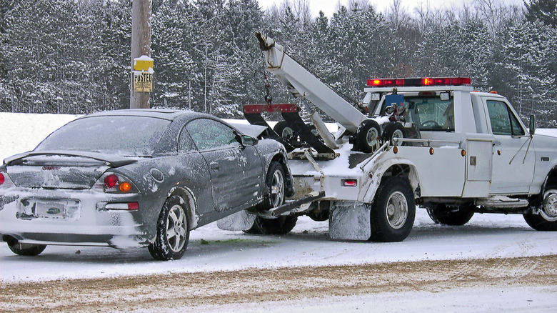 A tow truck pulling a car in the snow