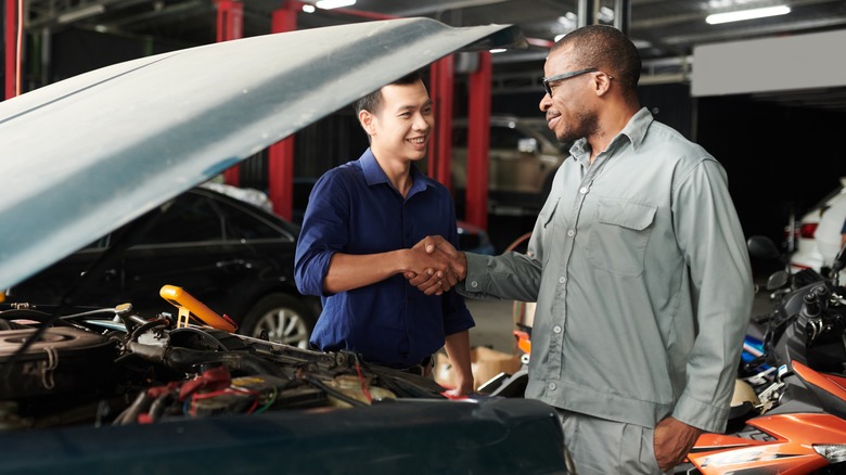 Car mechanic shaking hands