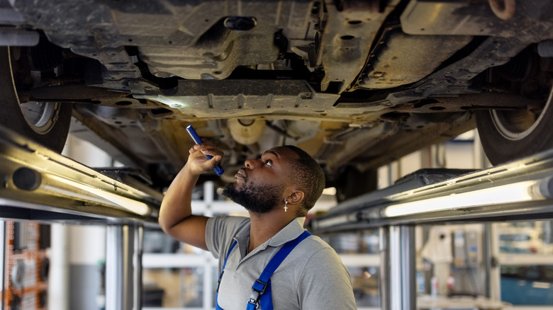 Mechanic examining underside of car