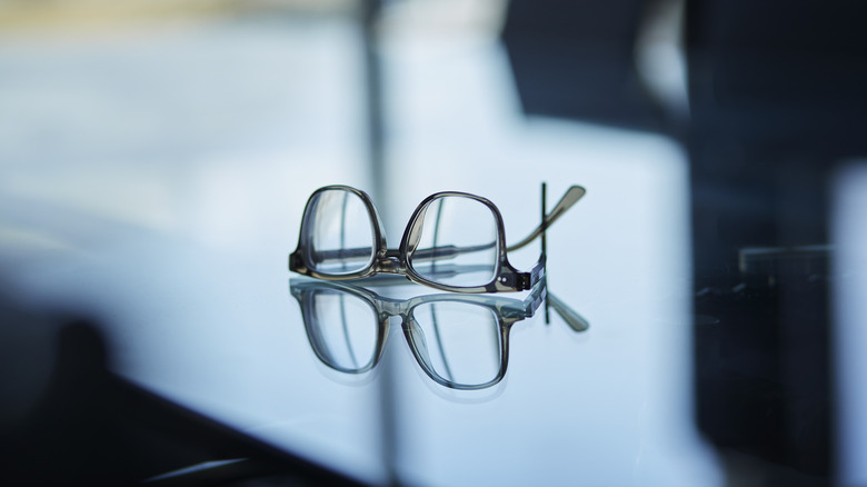 A glass desk in a boardroom with reading glasses on it