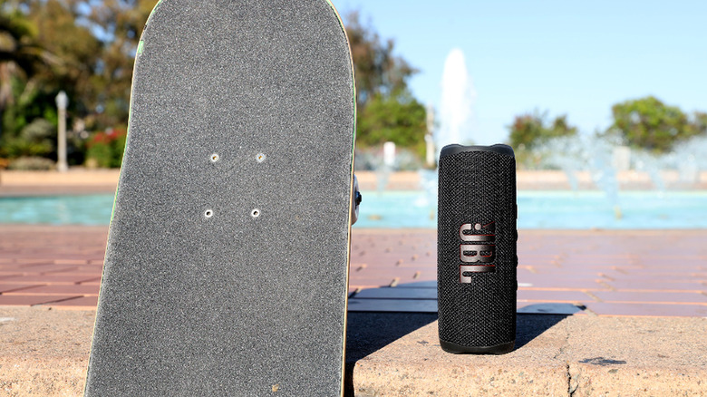 JBL speaker and skateboard next to pool