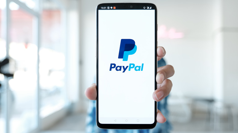 Person holding device with PayPal logo