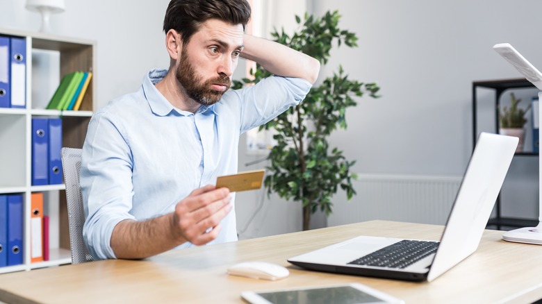 Unhappy man holding credit card