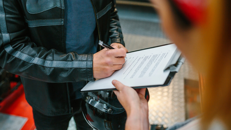 Biker signing papers in garage