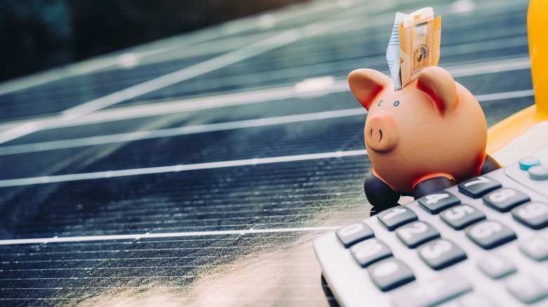 Calculator and piggybank on a solar panel