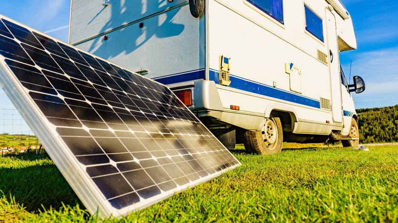 A portable solar panel is seen next to a camper van