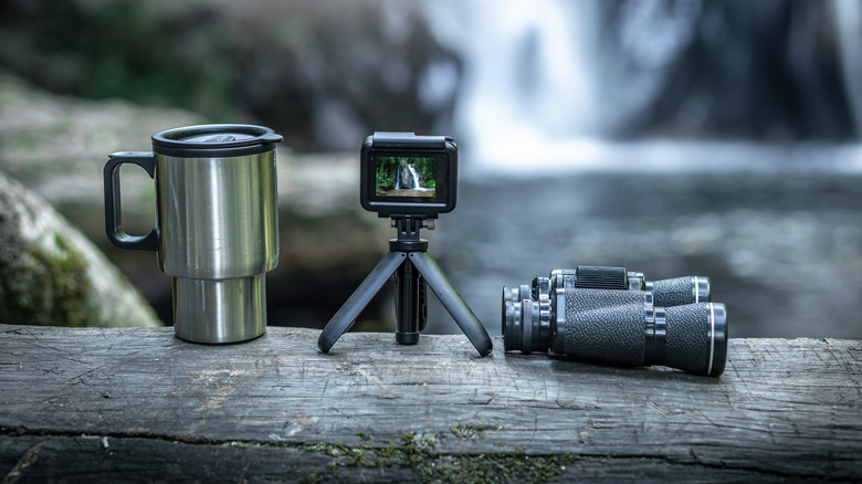 action camera, coffee cup and binoculars on wood