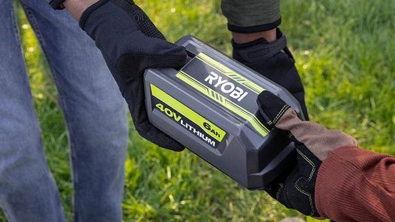 Person passing Ryobi 40V battery to another person