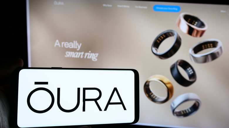 Oura logo on smartphone next to Oura Ring web page