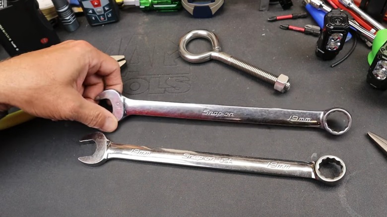 a person showing two snap-on combination wrenches