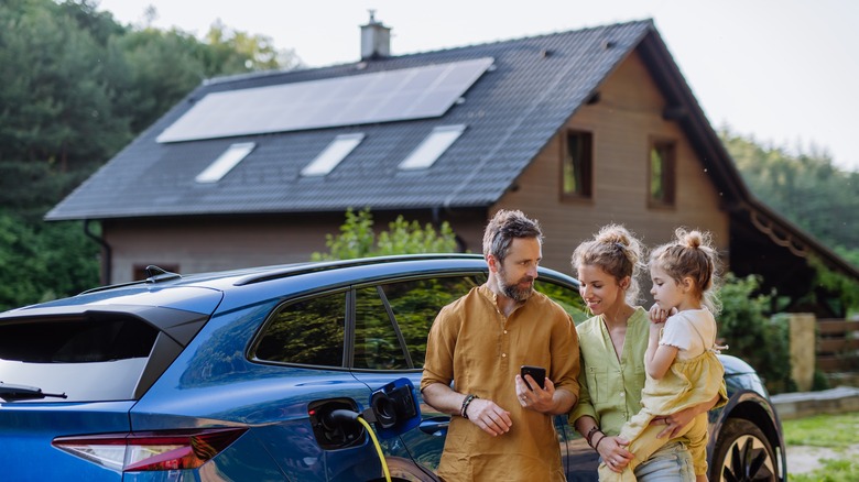 Family standing in front of a home with solar panel installations