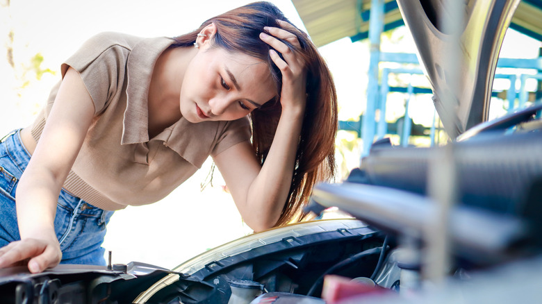 Woman Examining An Engine That Won't Start