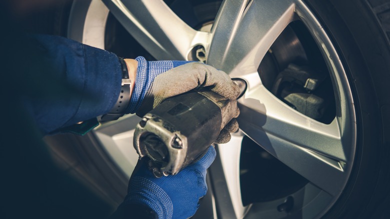 Person holding tool to car tire