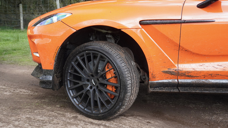 2025 Aston Martin DBX 707 front wheel, tire, and carbon fiber covered in mud