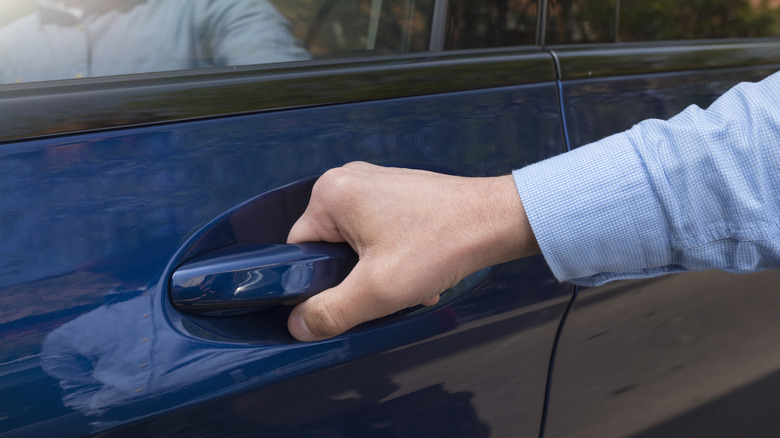 Man firmly grasping car door handle