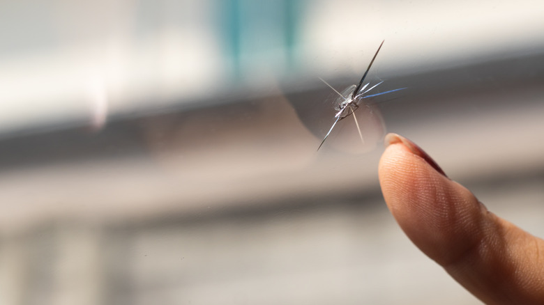 Finger pointing to a windshield crack