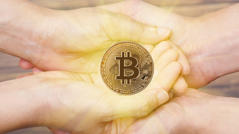 Hands cradling a Bitcoin token. 