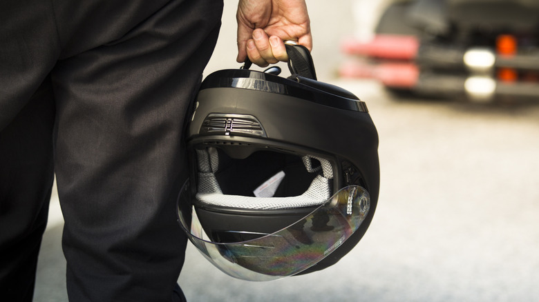 A man carrying a motorcycle helmet by its chinstrap