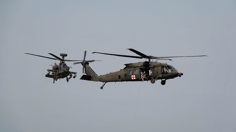 Apache helicopter flying behind Black Hawk