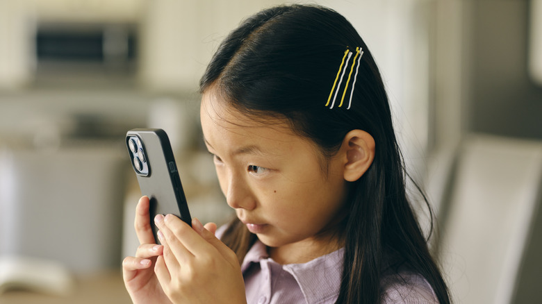 Child focusing on smartphone screen