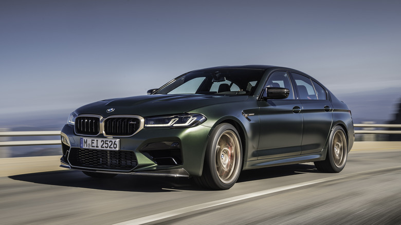 Green BMW M5 F90 driving fast on a public road