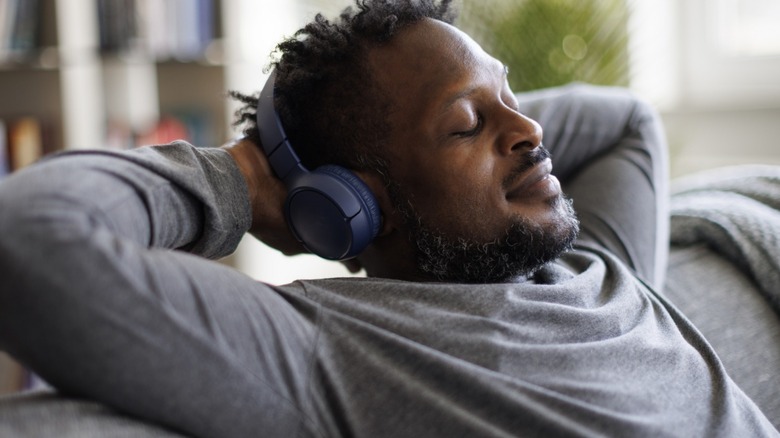 man laying back with his hands behind his head listening to music